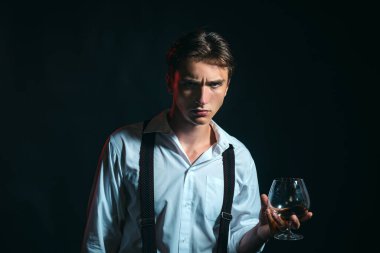 Klasik giyimli şık ve şık bir adam ve bilge bir adam. Bir bardak viski tutan şık, zengin bir genç adam.