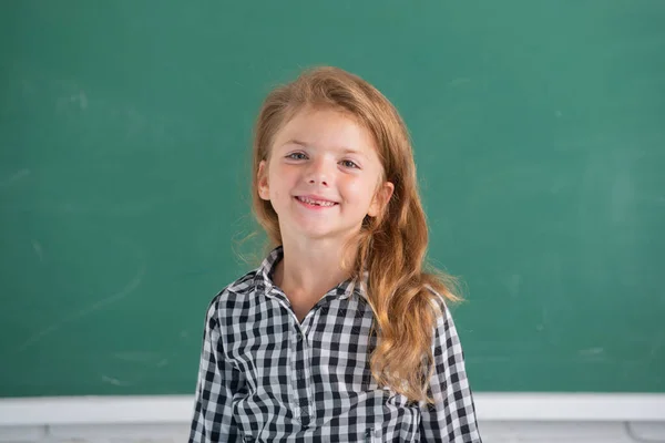 教室内のテーブルデスクトップに座って魅力的な小さな陽気な女の子のクローズアップ肖像画 面白い女子校生の顔だ 子供の教育と知識 学生の子供 — ストック写真