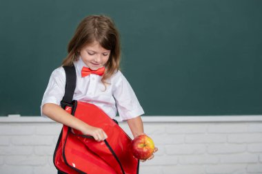 Sınıfta, okul üniformalı, sevimli, sırt çantalı bir kızın portresi. Çocukların eğitimi ve bilgisi. Öğrenci çocukları