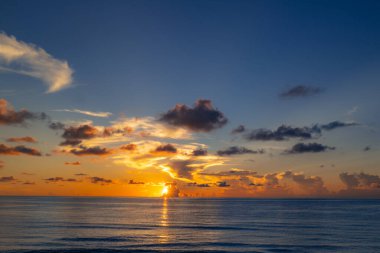 Tropikal deniz okyanusunda gün batımı ve gündoğumu bulutları. Seyahat tatili afişi. Manzara gökyüzü ve yansıma ışınları. Alacakaranlık, denizde alacakaranlık. Sakin, altın gökyüzü arka planı
