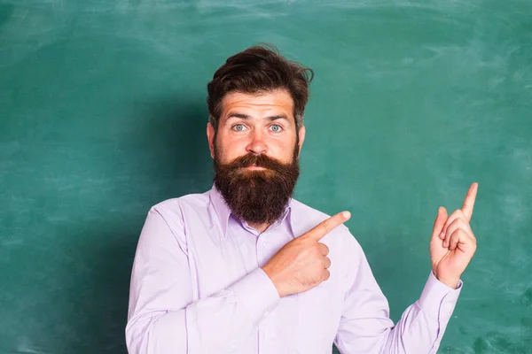 Blank chalkboard with copy space. Portrait of a funny teacher or professor near blackboard. Thinking serious mature teacher. Mature professor, middle aged teacher, bearded man. Study concept