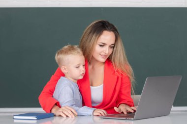 Anne ve oğul öğreniyor. İlkokul öğretmeni ve öğrenci online olarak sınıfta dizüstü bilgisayar kullanarak Webinar öğreniyor. Anne ve oğlu birlikte bilgisayar laptopu kullanıyorlar.