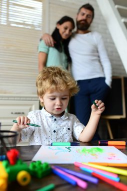 Mutlu bir aile eğleniyor, ebeveynler ve küçük çocuklar evde ödev yaparak kitap yazıyorlar. Erken çocukluk eğitimi, çocukların yaratıcı büyüme