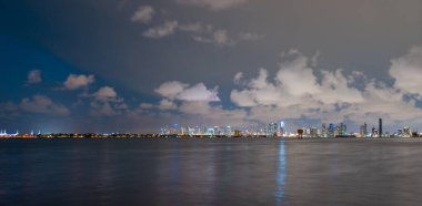 Miami şehri. Alacakaranlıkta deniz üzerinde gökdelenlerle Miami gökyüzü manzarası. Sanset 'te gece