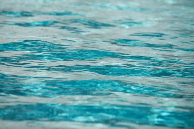 Yüzme havuzundaki mavi suyun arka planında güneş yansıması, havuzda dalgalı su dalgaları. Temiz su arkaplanı