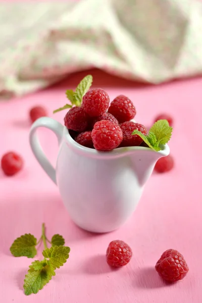 Raspberries in a white jug with mint — Stock Photo, Image