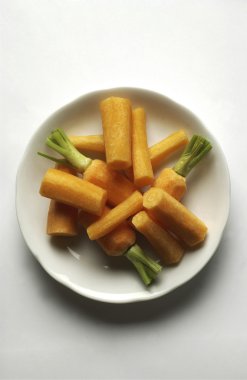 Beyaz plaka soyulmuş turuncu havuç yeşil yaprakları