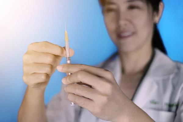 아시아의 의사가 백신으로 주사기를 환자에게 주사하기 복용량을 측정하는 스톡 이미지