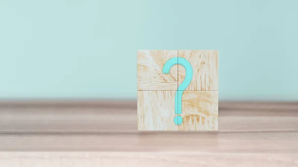 Business concept of Answers to Q&A. Question Mark (?) word in wooden cube blocks on wood table with cyan wall background.