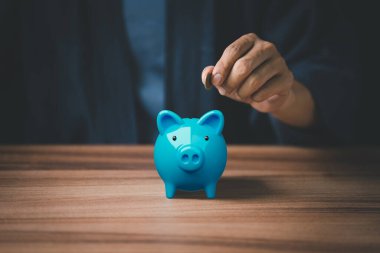 Adam para biriktirmek için kumbaraya para koyuyor..