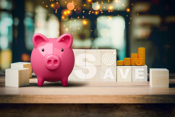 Pink piggy bank with SAVE words on wooden cube in abstract bokeh interior cafe backdrop. Business finance concept of planning, saving money wealth, financial and investment.