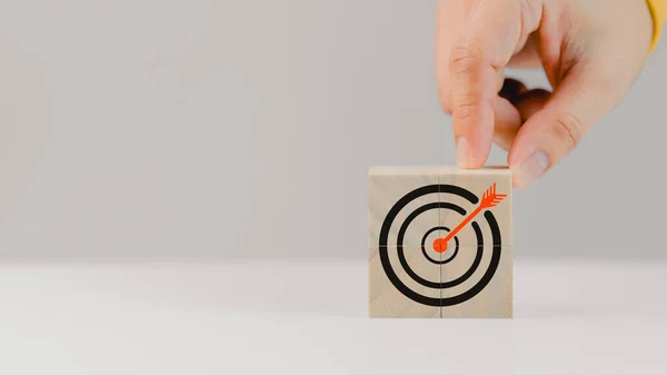 Hand put a goal icon on wooden cubes block on wood table. Business growth and goal in next year concept