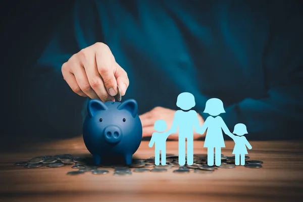Father putting coins on piggy bank with family icon on the table. Concept savings money for education, travel, family financial plan, retire, investment, financial crisis, health.