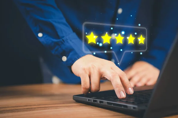 Man using laptop computer to rate service experience in application online. Customer reviews opinion poll satisfaction survey and testimonial.