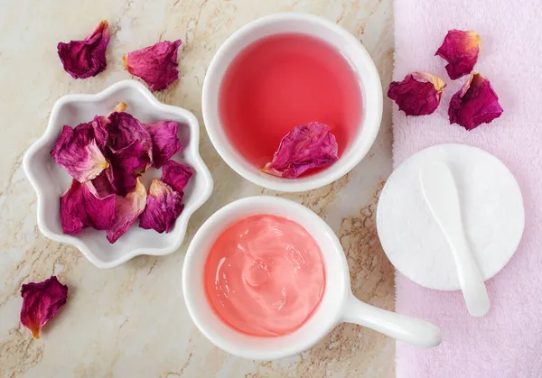 两个小的白色碗与玫瑰水 和果冻玫瑰面具 干玫瑰花瓣 制备自制化妆品的配料 自然美处理配方 零废物概念 — 图库照片