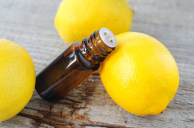 İçinde limon yağı bulunan küçük şişe (özü, tütsü, zerk, parfüm). Aromaterapi, spa ve bitkisel ilaç malzemeleri. Eski ahşap arka plan. Boşluğu kopyala 