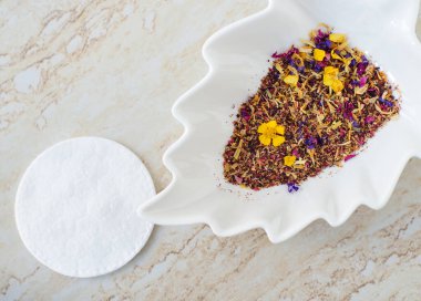 Kuru bitki ve çiçeklerle dolu küçük beyaz bir kase. Doğal cilt bakımı konsepti, ev yapımı spa, güzellik tedavi tarifi. 