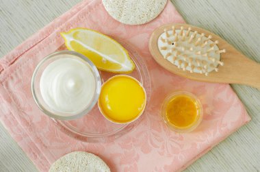 Çiğ yumurta sarısı, Yunan yoğurdu (ekşi krema veya kefir), yeşil yüz ve saç maskeleri, önlük ve nemlendirici hazırlamak için limon ve ahşap saç fırçası. Ev yapımı güzellik tedavi tarifi. Üst görünüm, alanı kopyala