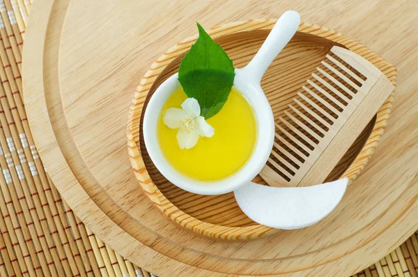 Kozmetik aroma yağı, pamuk göz bandı, ahşap saç fırçası ve beyaz yasemin çiçekli küçük beyaz kase. Doğal cilt bakımı, ev yapımı spa ve güzellik tedavi tarifi. Üst görünüm, alanı kopyala. 