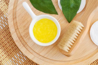 Küçük beyaz bir kase ve ahşap vücut fırçasında ev yapımı limon meyve fırçası (maske). Doğal güzellik tedavisi ve spa tarifi. Üst görünüm, alanı kopyala. 