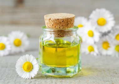 Roma papatya yağı içeren küçük cam bir şişe. Aromaterapi, spa ve bitkisel ilaç malzemeleri. Eski tahta arkaplan. 