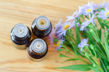 Üç küçük şişe ve gerekli yağ. Aromaterapi, spa ve bitkisel ilaç malzemeleri. Üst manzara, ahşap arkaplan.