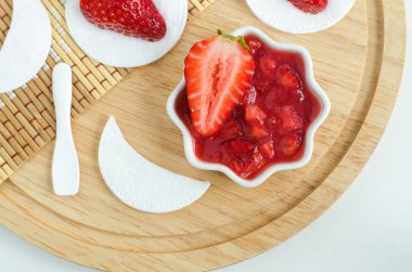 Küçük beyaz bir kasede ev yapımı çilek surat ya da göz maskesi. Doğal güzellik tedavisi ve spa tarifi. Üst görünüm.