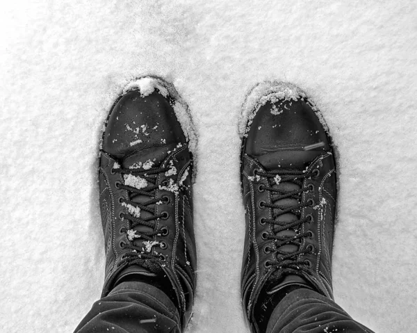 A man in boots stands on the snow. Legs close-up. Black and white photo. High-quality photo