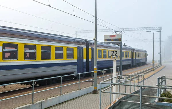 Railroad station with train old cars and people getting into wagons, photo was taken in famous European resort city of Jurmala during morning fog at spring time