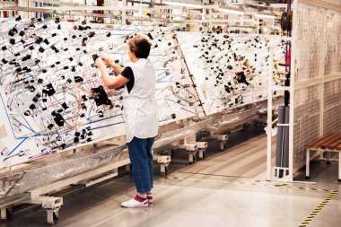 Bir işçi bir üretim odada elektrik kablolama araçlık bir modern fabrikasında üretim için standları