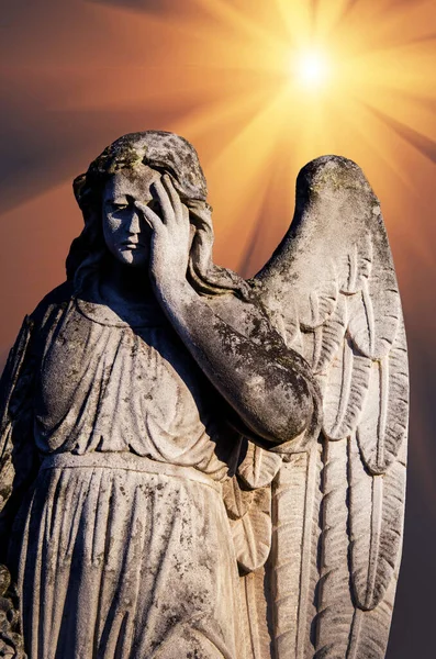 希望を象徴する光の光線を背景に 死者を悼む悲しい天使の古代彫刻 — ストック写真