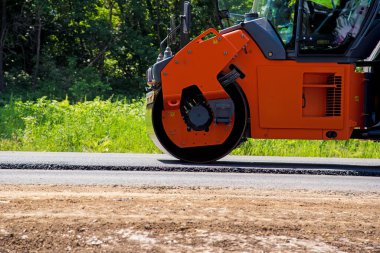Yolda yeni bir asfalt yuvarlayan tekerlekli sanayi manzarası. Onarım, karmaşık ulaşım hareketi.