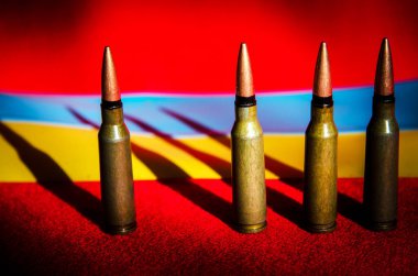 Ukrayna bayrağı ve kan renginin arka planında askeri mermilerin soyut görüntüsü (Ukrayna Savaşı - kavram)