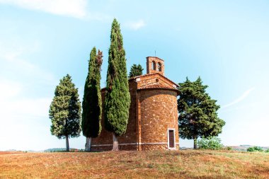 İtalya 'nın Toskana kentindeki San Quirico d' Orcia 'da (Val d' Orcia) güneşli bir günde Madonna di Vitaleta şapeli ile sihirli bir manzara. Mükemmel turistik yerler..