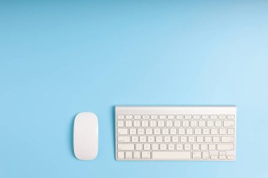 Mavi masa. İş aletini masaya koyun. Üst görünüm ofis masası klavyeli, ve mavi arkaplanda da kopya alanı olan fare. Konsept iş ofisi, finans ve teknoloji.