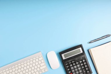 Mavi masa, iş için gerekli aletleri masaya koyun. Klavyesi, hesap makinesi, faresi, kalemi ve defteri olan en üst düzey ofis masası. Boş mavi arkaplan kopyalama alanı.
