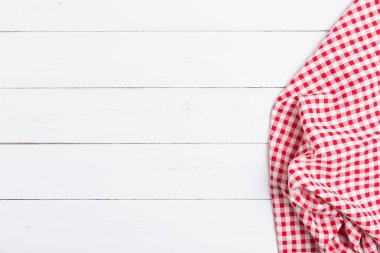 Ahşap beyaz masa üzerinde kırmızı ve beyaz masa örtüsünün üst görüntüsü. Restoranlara metin menüsü için kopyalama alanı olan düz pamuk yatıyordu.