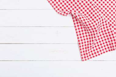 Ahşap beyaz masa üzerinde kırmızı ve beyaz masa örtüsünün üst görüntüsü. Restoranlara metin menüsü için kopyalama alanı olan düz pamuk yatıyordu.