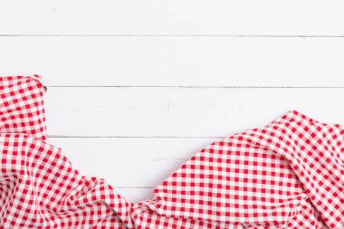 Ahşap beyaz masa üzerinde kırmızı ve beyaz masa örtüsünün üst görüntüsü. Restoranlara metin menüsü için kopyalama alanı olan düz pamuk yatıyordu.