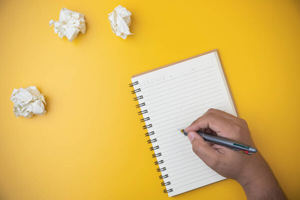 Копировальное пространство на рабочем столе. Плоская лежала рука человека, держащего ручку на блокноте на желтом фоне. Бизнес, технологии, изучение и обучение концепции. 