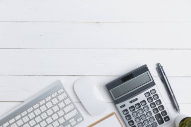 Top view table business of office with copy space. The desk in an office with equipment stationery business with keyboard, mouse, notebook, a pen, and calculator on an old white wooden table. 