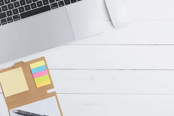 The desk in an office with equipment stationery business with laptop, mouse, notebook, a pen on an old white wooden table. Top view table business of office with copy space.