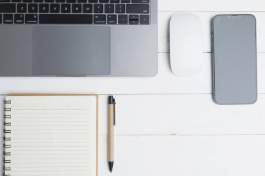 The desk office with a laptop, smartphone, blank notepad, and pen on a wood table. Flat lay top view copy space. Concept business technology.