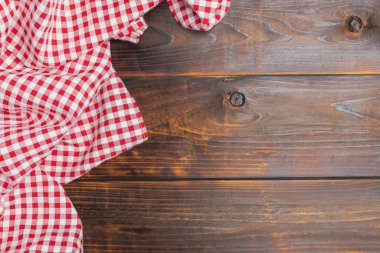 Checkered red and white on an old wooden background with copy space, top view. Fabric texture background. The texture of the cotton fabric. With copy space for design menu of food for the restaurant.
