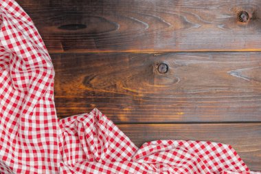 Checkered red and white on an old wooden background with copy space, top view. Fabric texture background. The texture of the cotton fabric. With copy space for design menu of food for the restaurant.