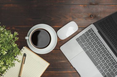 Flat lay, top view. Old wood office table. Top view desk of work office with laptop, stationery, a pen, green leaf, and coffee of cup on old wooden background with copy space.