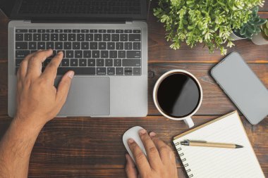 Top view desk of work office with laptop, smartphone, a pen, green leaf, and coffee of cup on old wooden. Businessmen use laptop information from home. work from home concept 