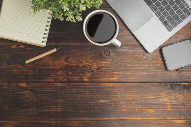 Flat lay, top view. Old wood office table. Top view desk of work office with laptop, stationery, a pen, green leaf, and coffee of cup on old wooden background with copy space.