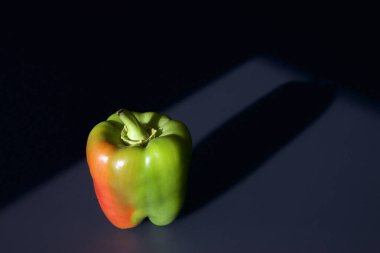 A single Bell Pepper on the kitchen table with black background.