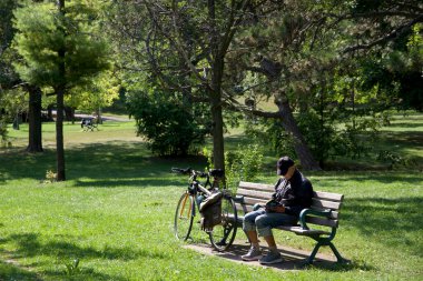 Toronto, Ontario / Kanada - 09 / 15 / 2020: Park bankında oturmuş kitap okuyan bekar bir adam